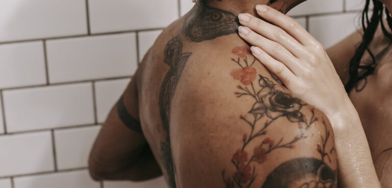 Side view of crop anonymous female stroking nude ethnic beloved while standing in bathroom together